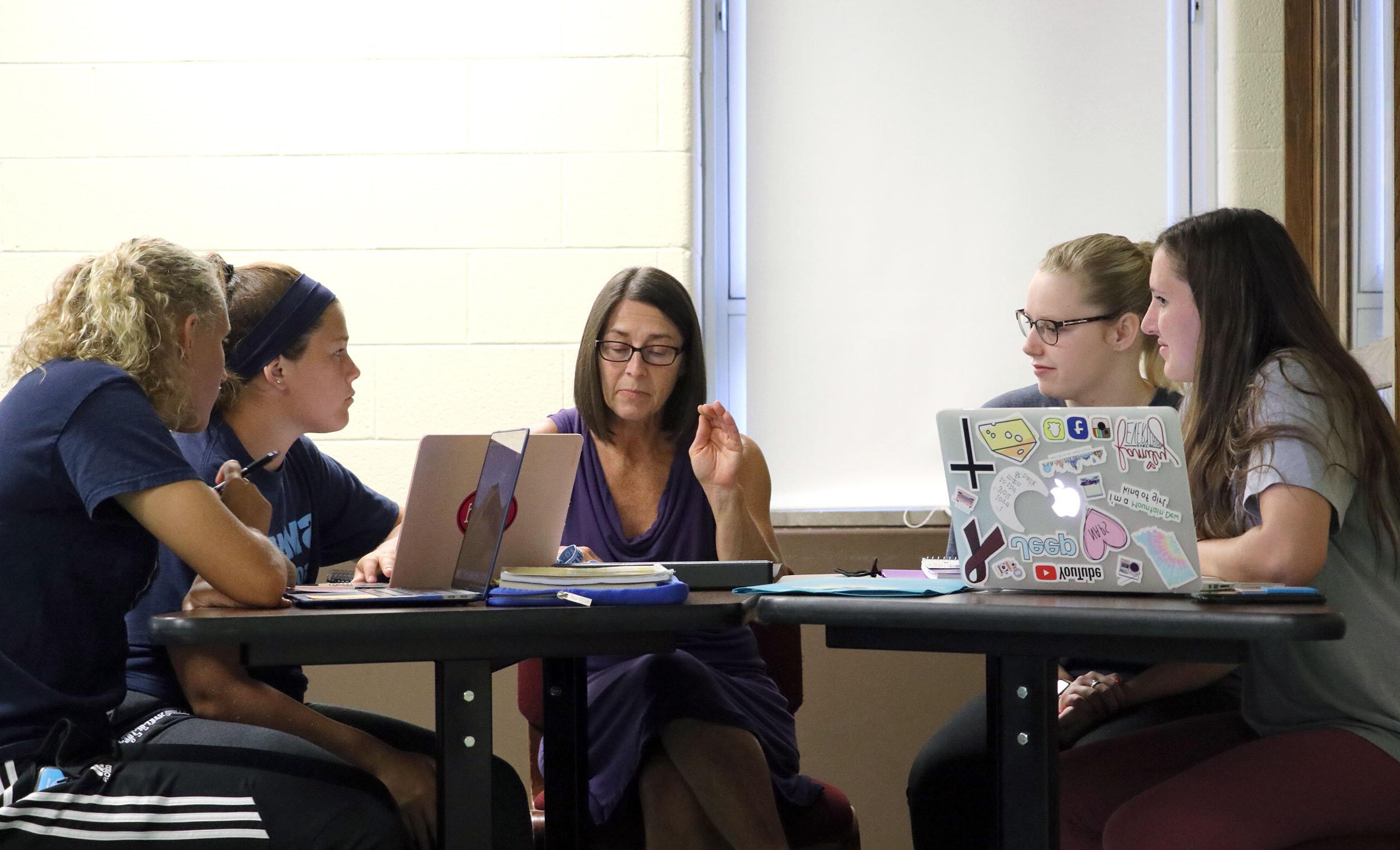 Four students meeting with a professor